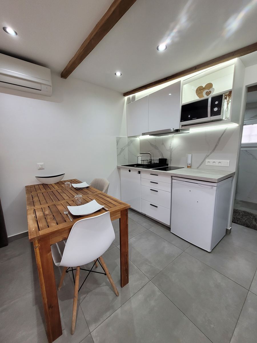 Studio avec kitchenette et coin repas repeints en blanc, poutre apparente — réalisation Artisan Peintre 06